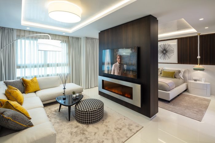This image shows the master suite with lounge area. Central column houses the TV and fireplace. Another screen hangs on the other side of the column for watching TV in bed.