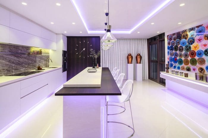 Kitchen island and breakfast bar. Floating cabinet with LED lighting sits under the artwork. The colour of the lighting can be changed to match any colour in the artwork above.